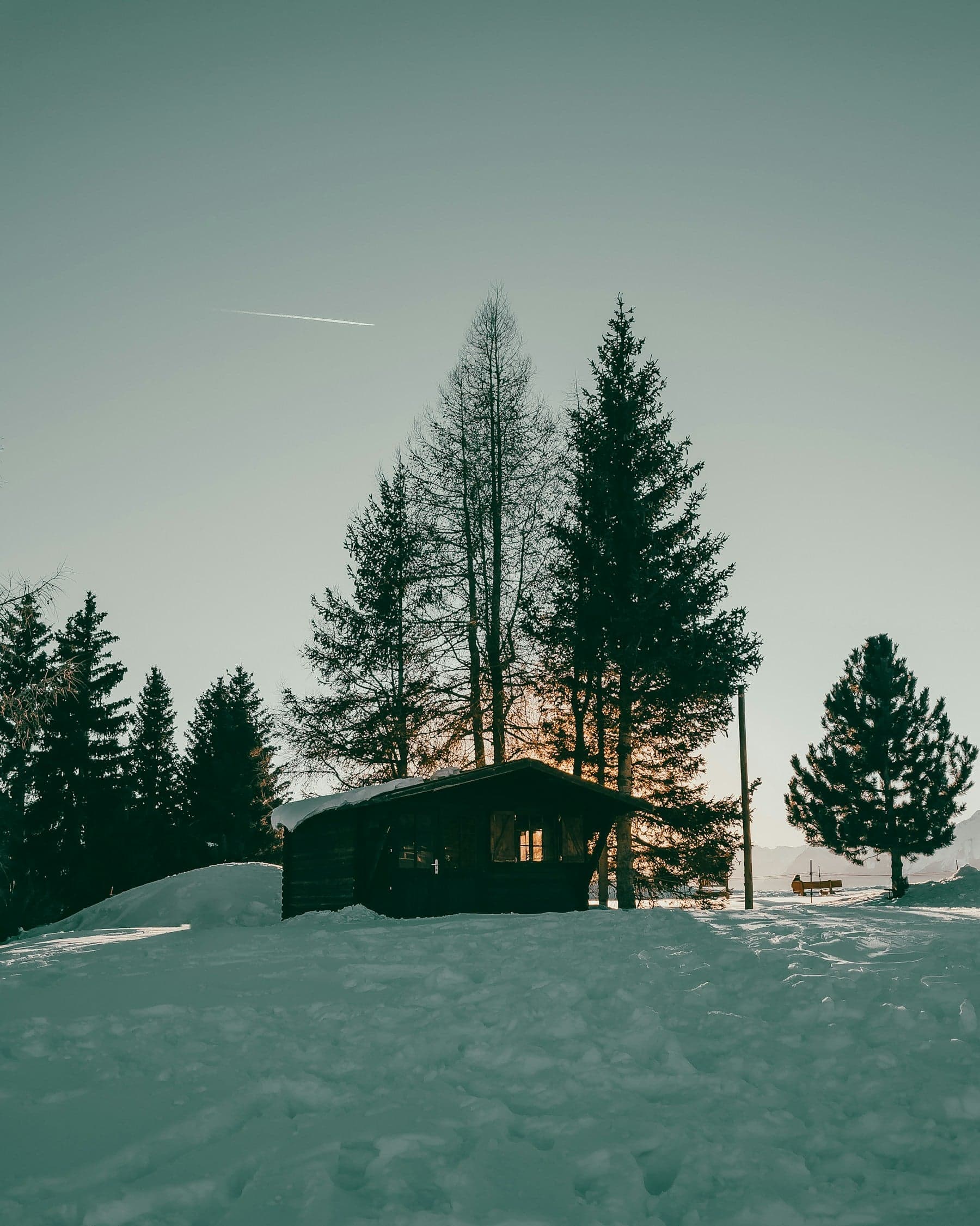 Snow-covered cabin near Crans-Montana at sunset