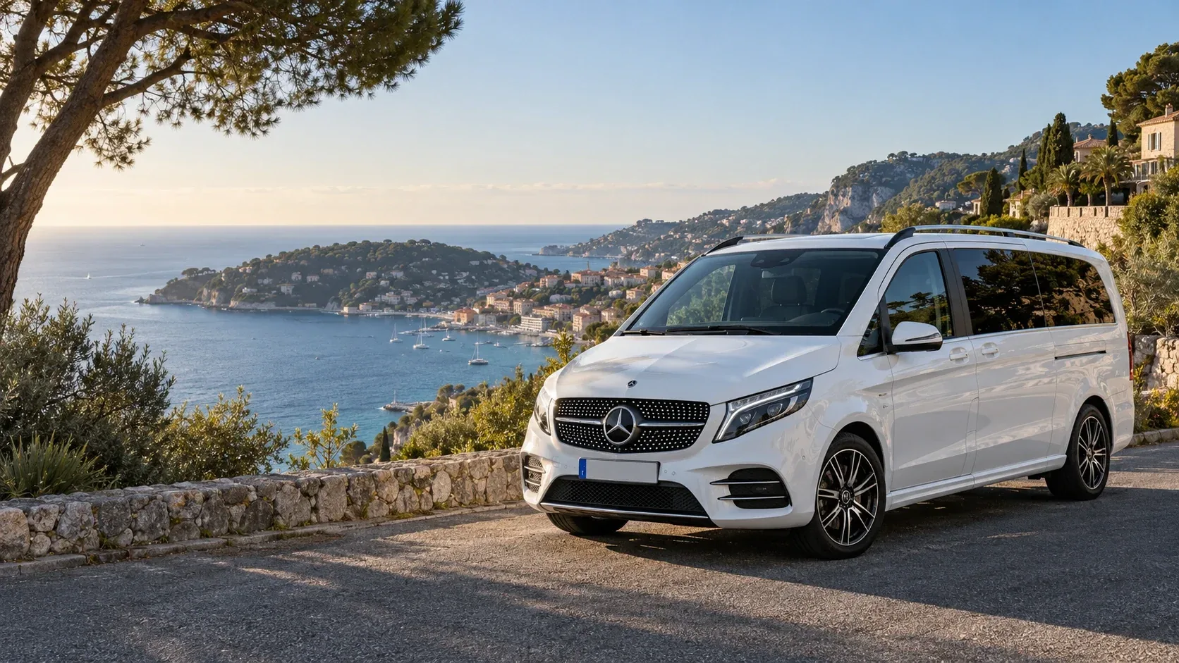 White Mercedes-Benz V-Class parked on a coastal road overlooking the French Riviera.